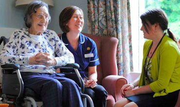 Care professionals speaking with an older adult at home